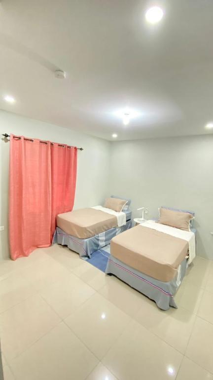 PiarcoSerenity Condo的一间设有两张床和红色窗帘的房间
