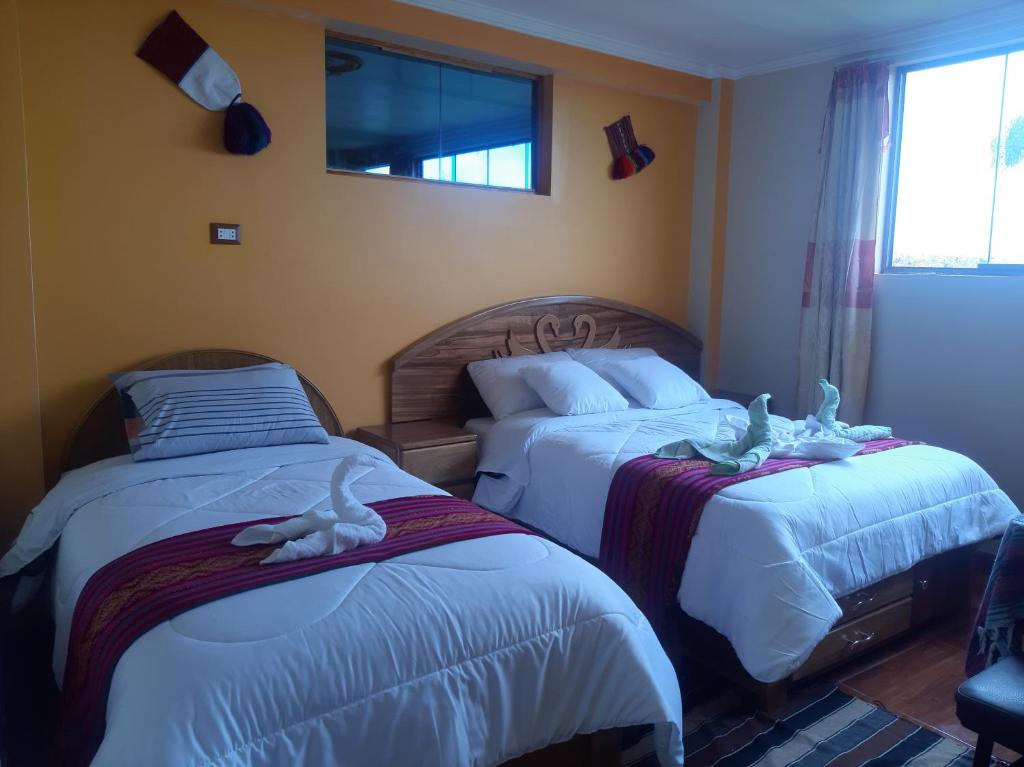 HuillanopampaTaquile Inti Raymi Lodge的一间卧室设有两张床,里面饲养着动物。