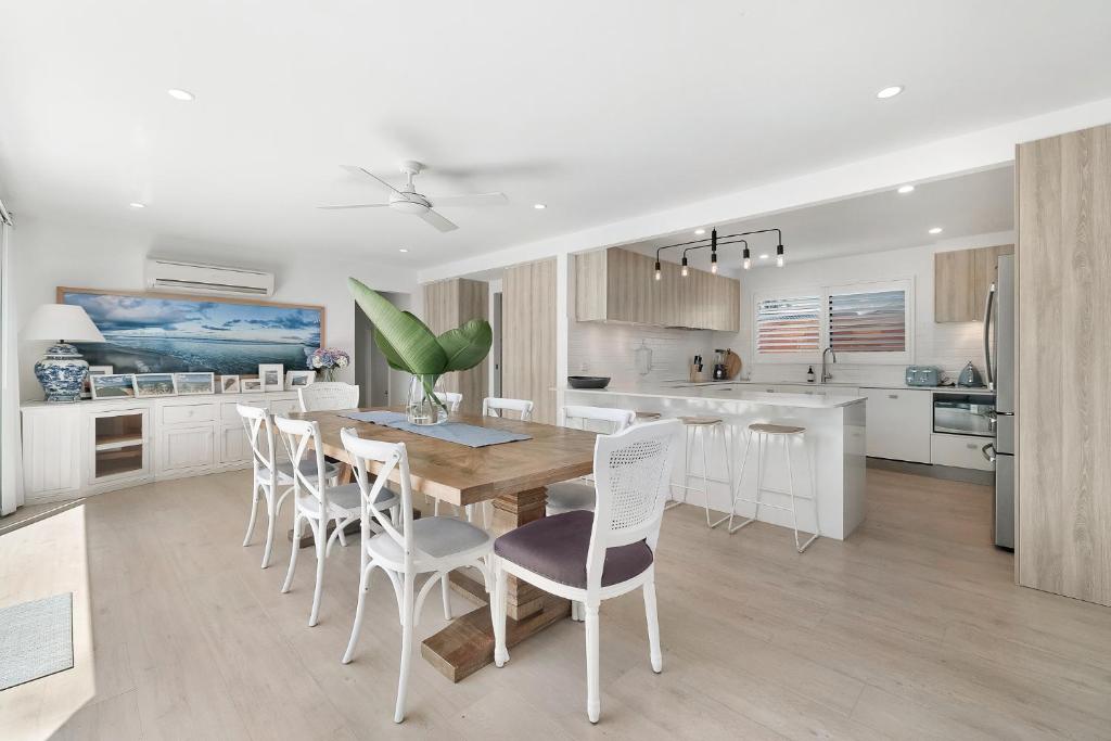 黄金海岸5BR Mermaid Waters Luxury Home的厨房配有木桌和白色椅子