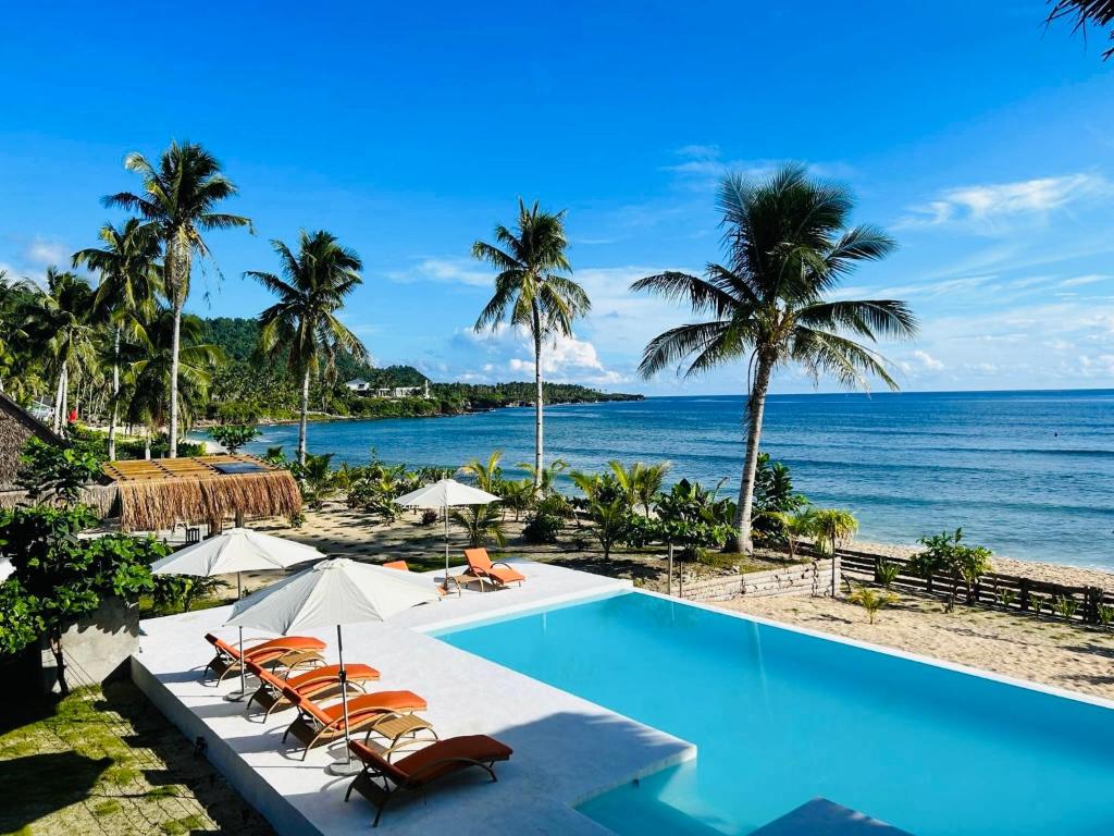San IsidroYapak Beach Villas的棕榈树海滩旁的游泳池