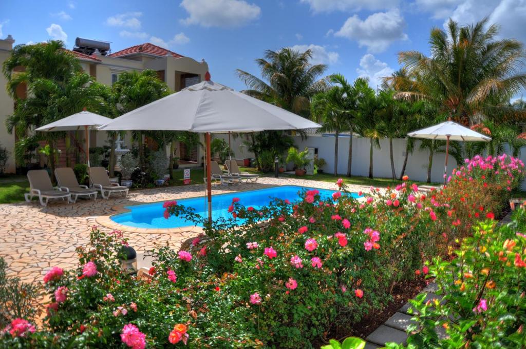 康隆尼角伯恩特别墅酒店的一个带遮阳伞和鲜花的游泳池