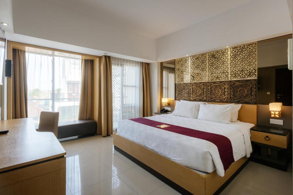 塞米亚克Horison Ultima Seminyak Bali - CHSE Certified的酒店客房设有一张大床和一张书桌。