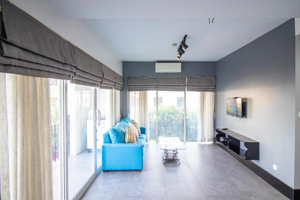 暹粒1 BR Serviced Apt In The Heart of Siem Reap的客厅设有蓝色的沙发和大窗户