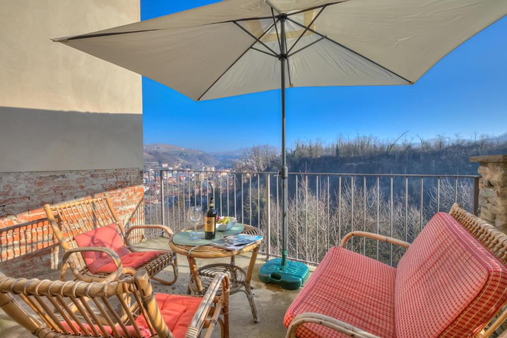 多利亚尼Dogliani Borgo Castello - Happy Rentals的庭院配有椅子和桌子及遮阳伞