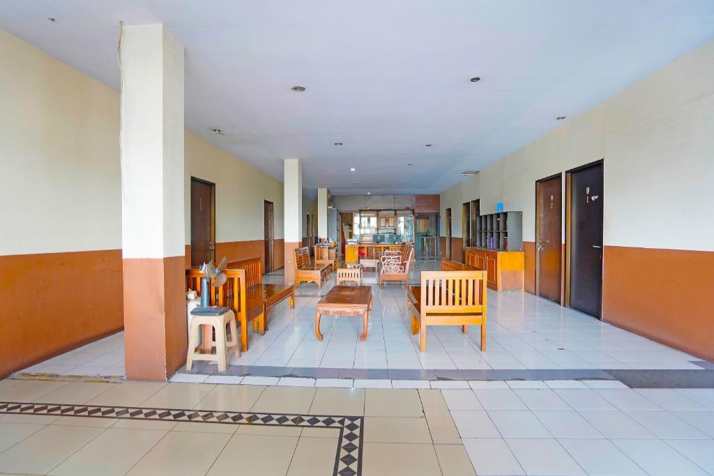BungurasihOYO 91415 De Wijaya Hotel的大楼内带桌椅的走廊