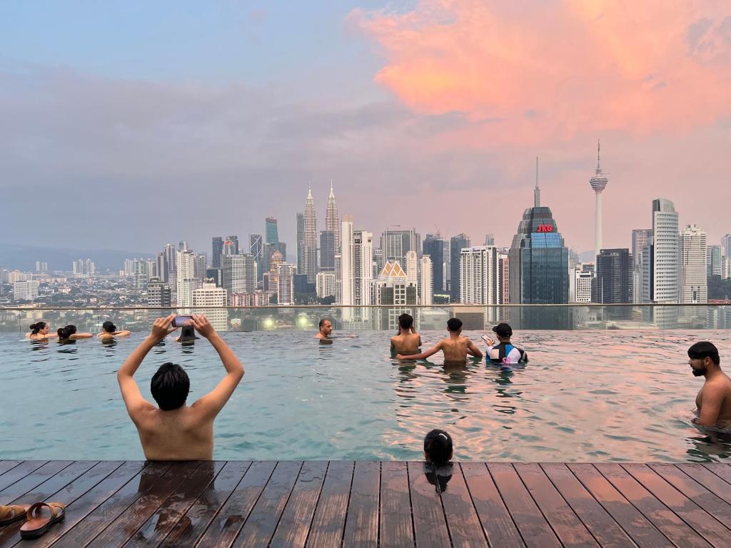 吉隆坡Empire Hostel Regalia的一群人在一座城市天际线的游泳池游泳