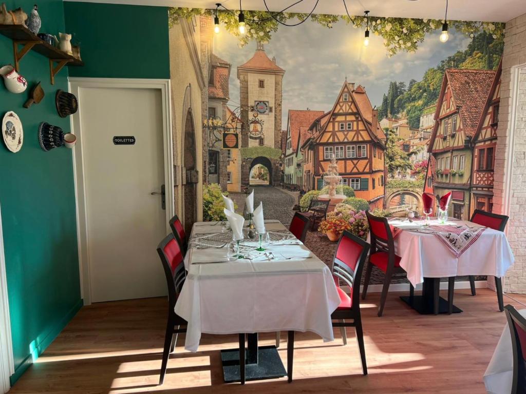 盖雷Hôtel Le Pommeil的一间设有两张桌子的用餐室和墙上的壁画