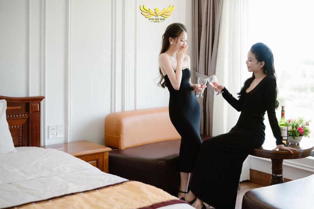岘港Phu My Hai Hotel的两名女士入住酒店客房,并享用葡萄酒