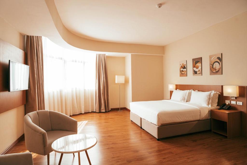 亚的斯亚贝巴AYA Addis Hotel的配有床、椅子和桌子的酒店客房