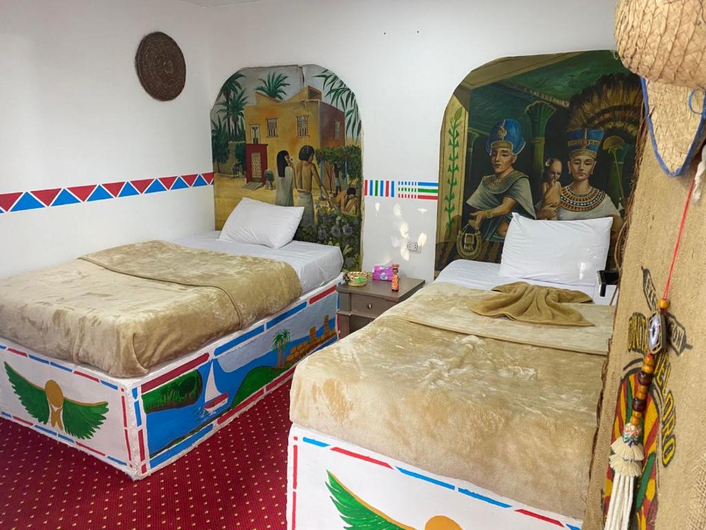 卢克索peace garden hostel & camp的墙上挂有绘画的客房内的两张床