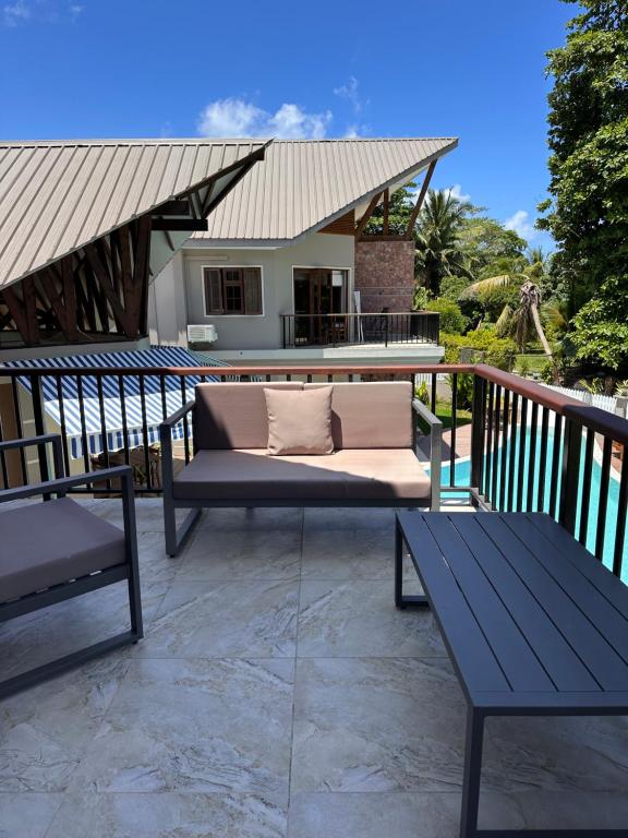 拉迪格岛Villa Source D'Argent的平台上设有带沙发和2张长凳的天井