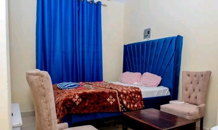 蒙巴萨Ziggon villa mtwapa的配有蓝色窗帘和桌子的床的客房