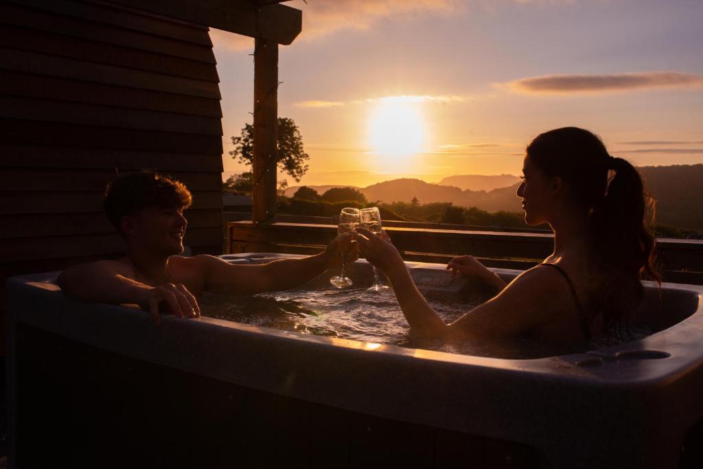 康威Tan Y Bryn Glamping的男人和女人坐在热水浴缸里,喝一杯葡萄酒