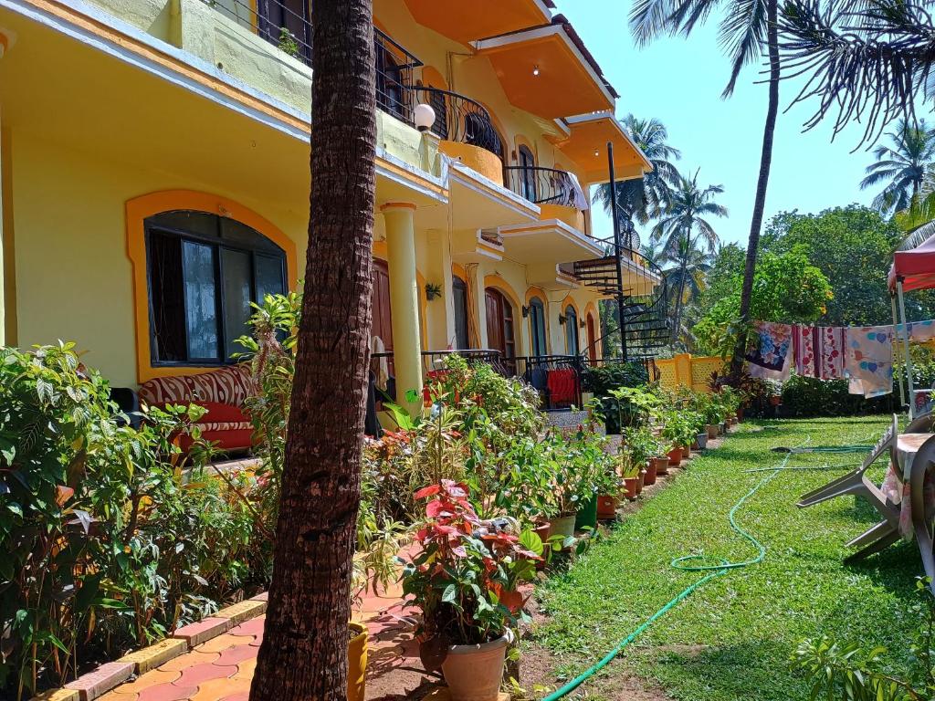 AguadaFLOBESTIAN BEACH VILLA CANDOLIM BEACH的院子前有软管的黄色建筑