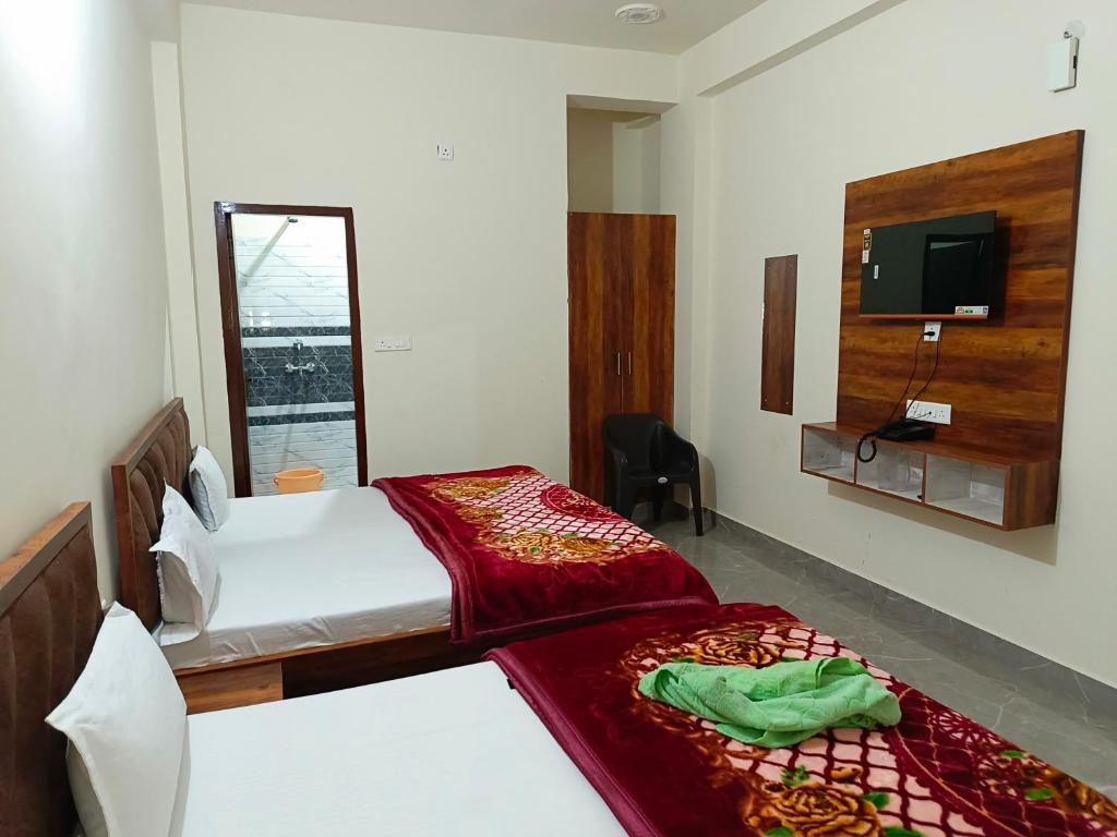 马图拉Shri Girraj Residency的一间卧室设有两张床,墙上配有电视。