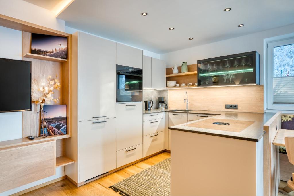 因斯布鲁克INN Sun Apartment的厨房配有白色橱柜和平面电视。