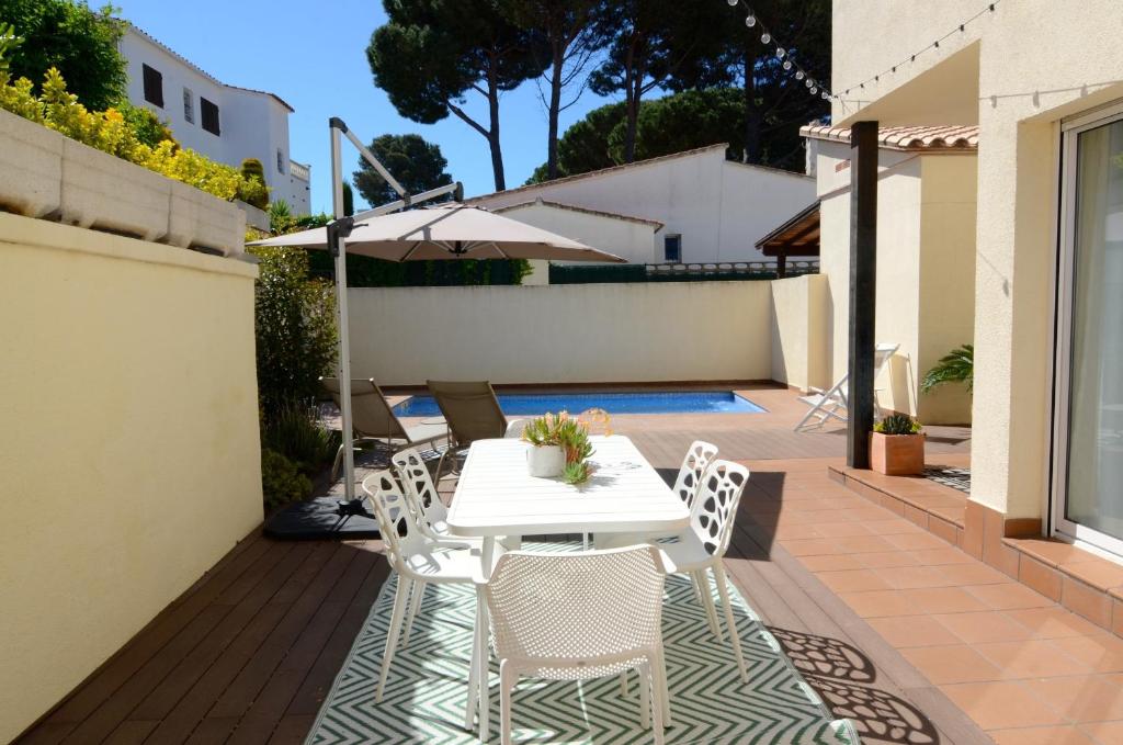 莱斯卡拉Casa Cossis的庭院配有白色的桌椅和遮阳伞。