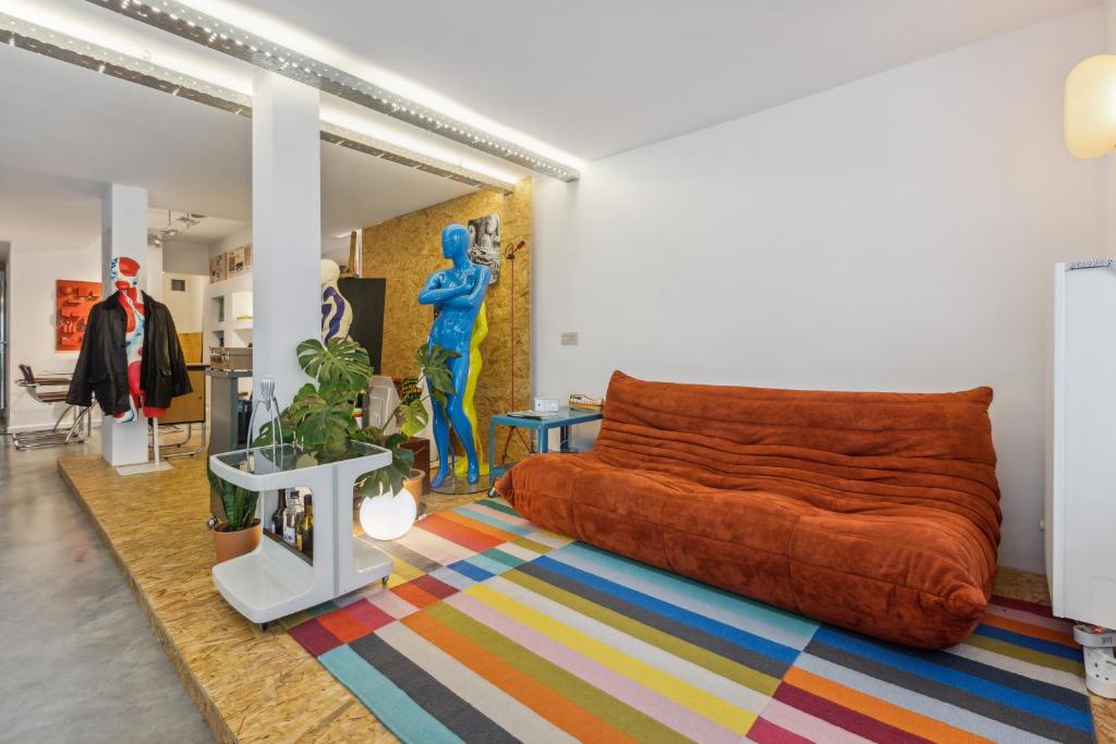 根特Cosy art studio near station with bikes and garden的客厅配有橙色沙发和色彩缤纷的地毯。