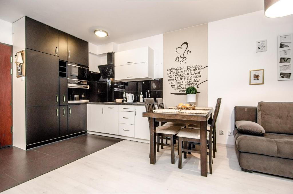 科沃布热格Apartament z Ogródkiem - Alldayholiday的厨房以及带桌子和沙发的用餐室。
