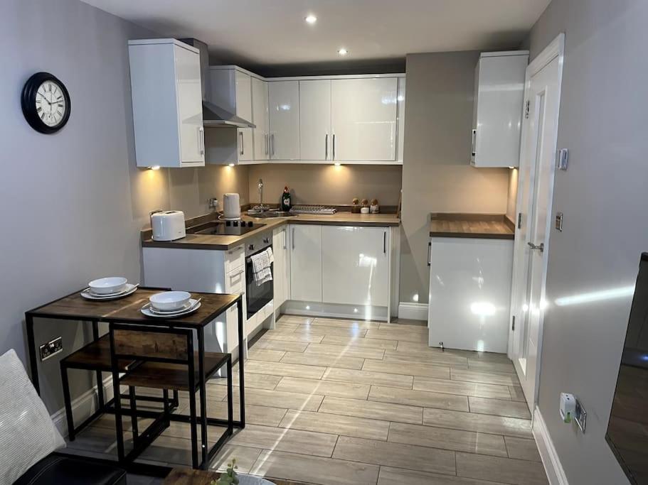 布莱顿霍夫City Centre Seaview Apartment的厨房配有白色橱柜和小桌子。