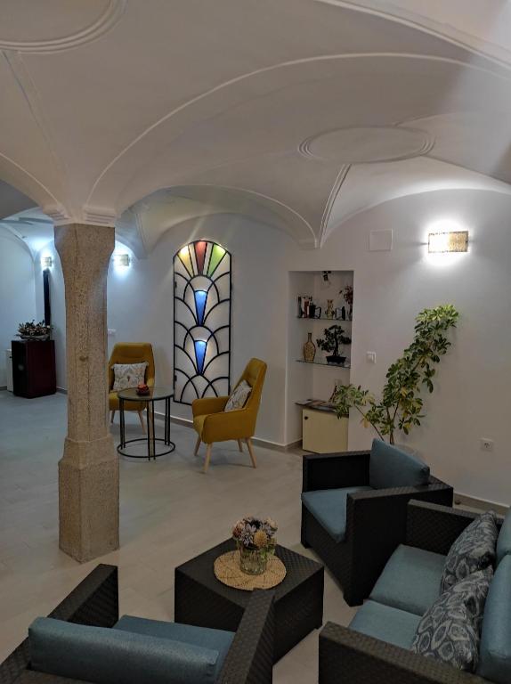 Calera de LeónCASA RURAL ELENYR的大堂配有沙发、椅子和彩色玻璃窗