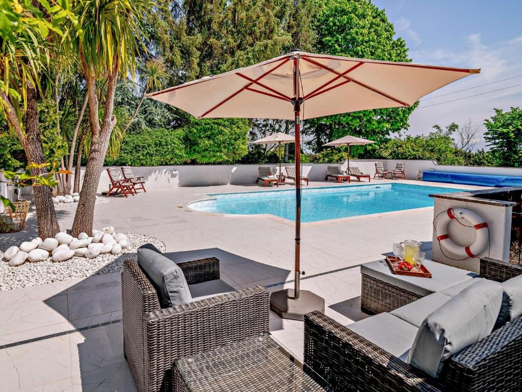 曼海德2 Bed in Minehead 90924的一个带遮阳伞和椅子的庭院和一个游泳池