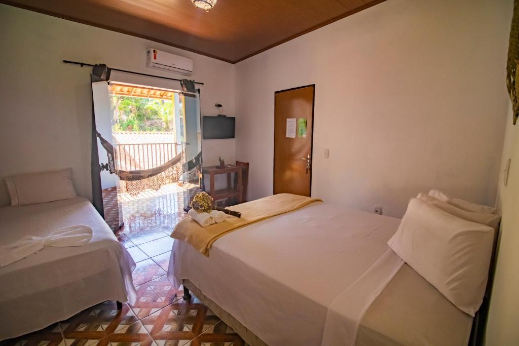 伦索伊斯Hospedaria Diamante Lençóis的一间卧室设有两张床和窗户。