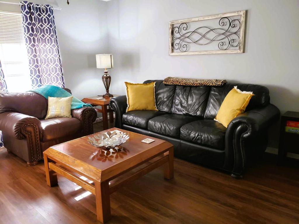 泰勒Midtown Southern Charm的客厅配有黑色真皮沙发和咖啡桌