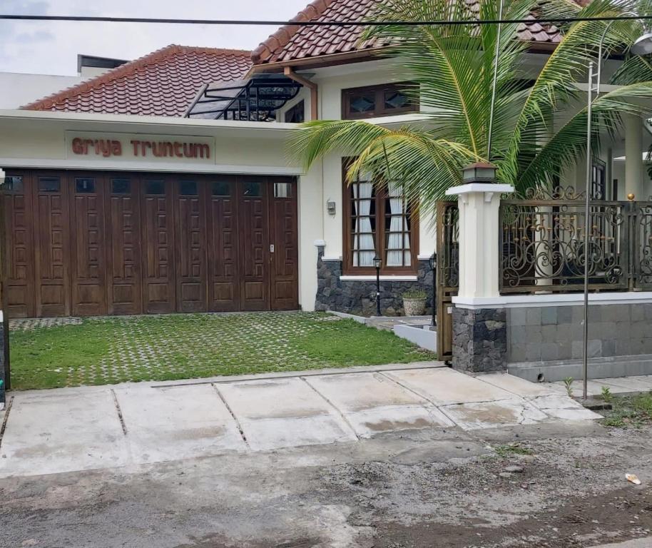 LaweanGuesthouse Syariah Griya Truntum的车库前有棕榈树的房子