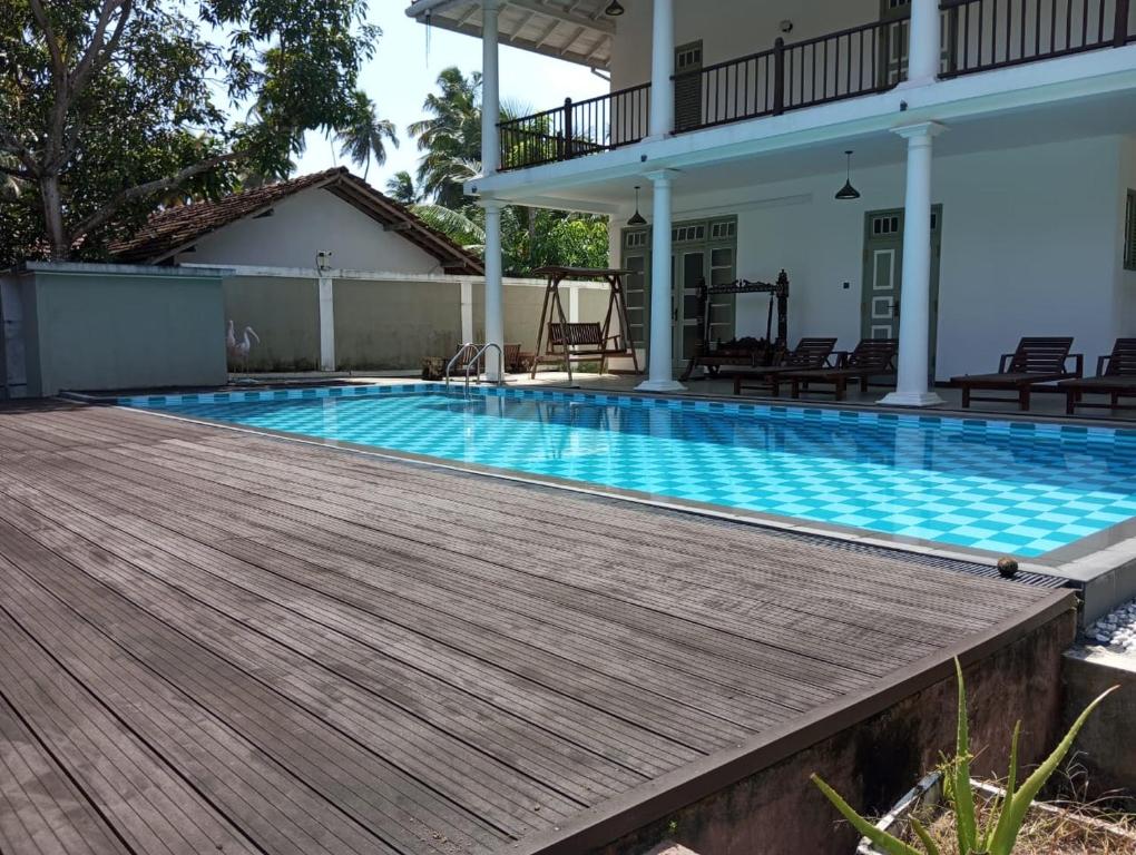 阿洪加拉Nade Villas Ahungalla的一座带木甲板的游泳池,位于一座房子旁边