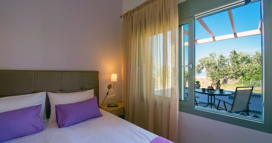 波托什Terra di Olive Thassos的一间卧室配有一张带紫色枕头的床和一个阳台