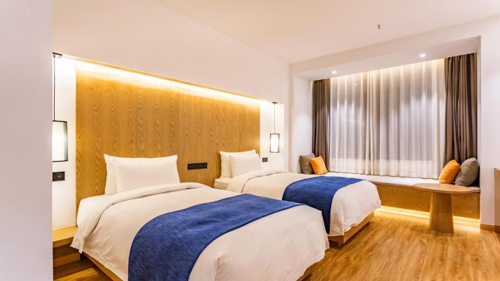 郑州素朴酒店(郑州CBD国际会展中心店)的酒店客房设有两张床和窗户。
