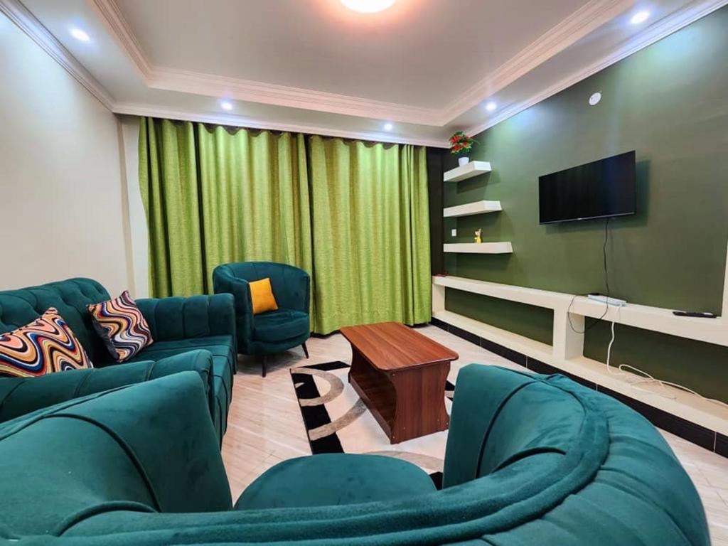 恩德培Del Cielo Serviced Apartments的客厅配有绿色家具和平面电视