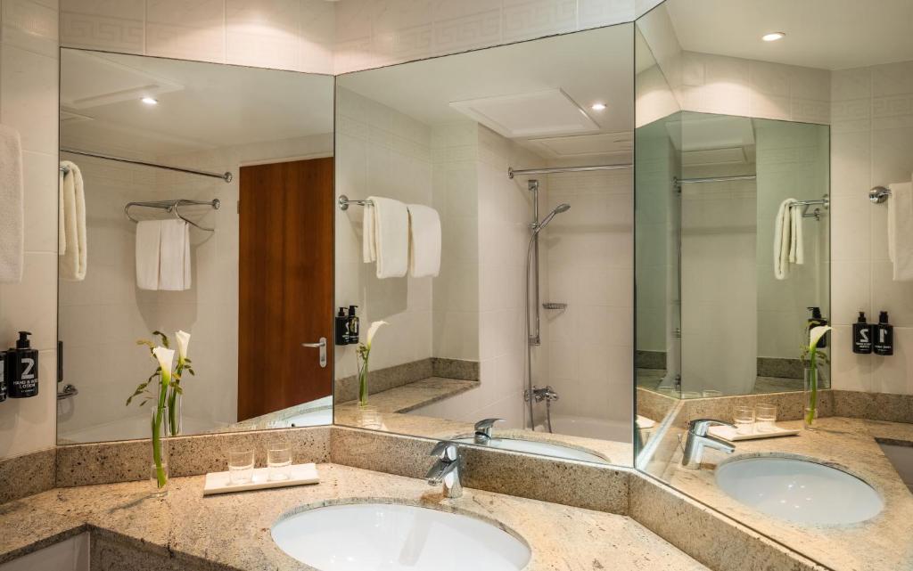 科特布斯Lindner Hotel Cottbus的带大镜子的浴室内的2个盥洗盆