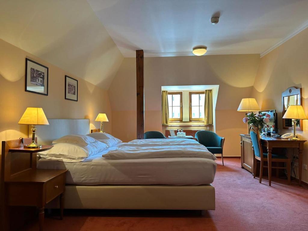 乌赫尔堡施朗斯酒店的卧室配有一张床、一张桌子和椅子