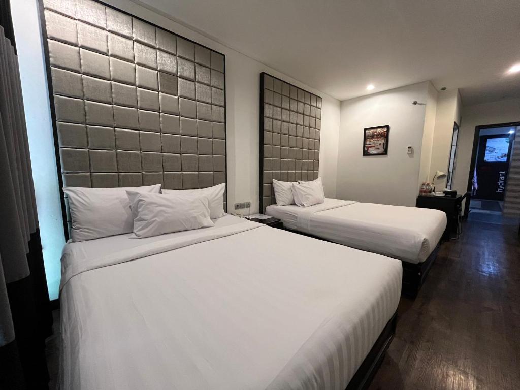 万隆Kalya Hotel Bandung Dago的配有白色床单的酒店客房内的两张床