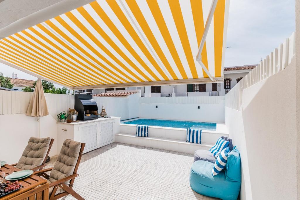 阿尔图拉StaySalty - Resort Style Family Beach House with Pool的庭院设有游泳池和黄色及白色的遮阳伞。