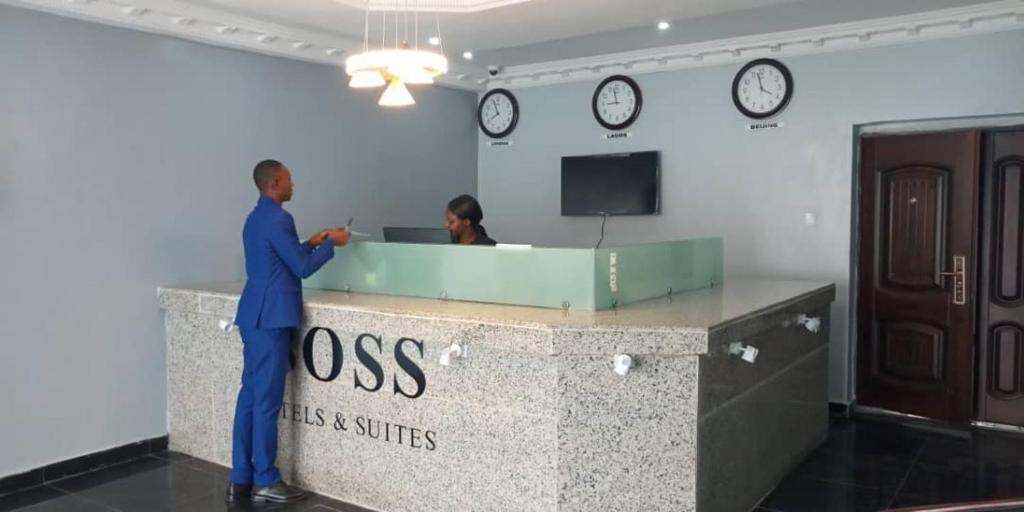 拉各斯BOSS HOTELS & SUITES的站在办公室桌子上,有两个钟表的人