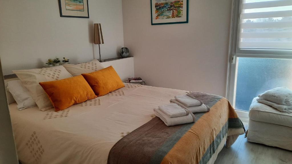 拉特斯特德布赫Dune的一间卧室配有带橙色枕头的床和窗户。