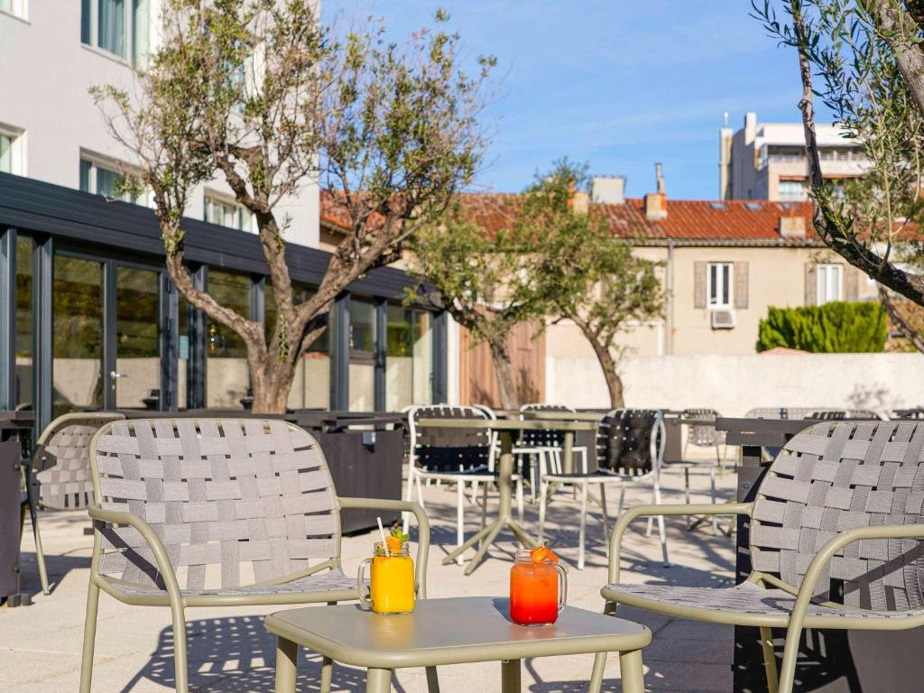 马赛马赛美居中心普拉多赛车场酒店的庭院里摆放着几把椅子和桌子