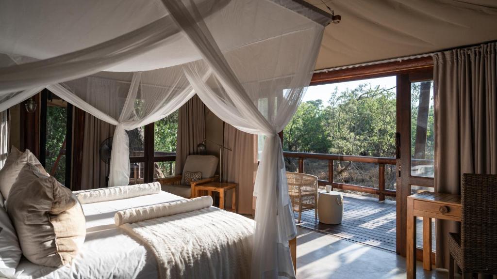 LentswelemoritiTuli Safari Lodge Mashatu的一间卧室设有一张天蓬床和一个阳台