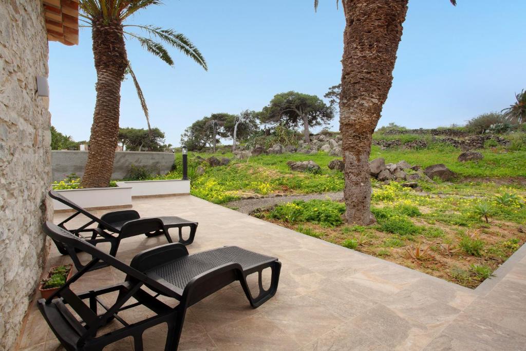 圣港Casa De Pedra的两把黑色椅子坐在棕榈树庭院