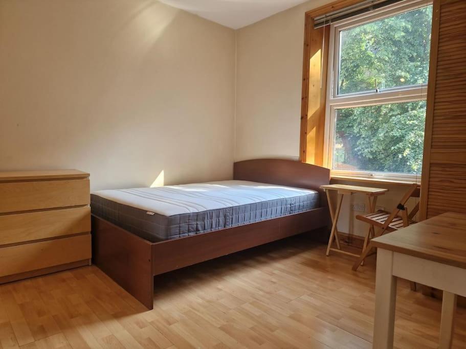 伦敦Bright studio apartment Highgate的一间卧室配有一张床、一张书桌和一个窗户。