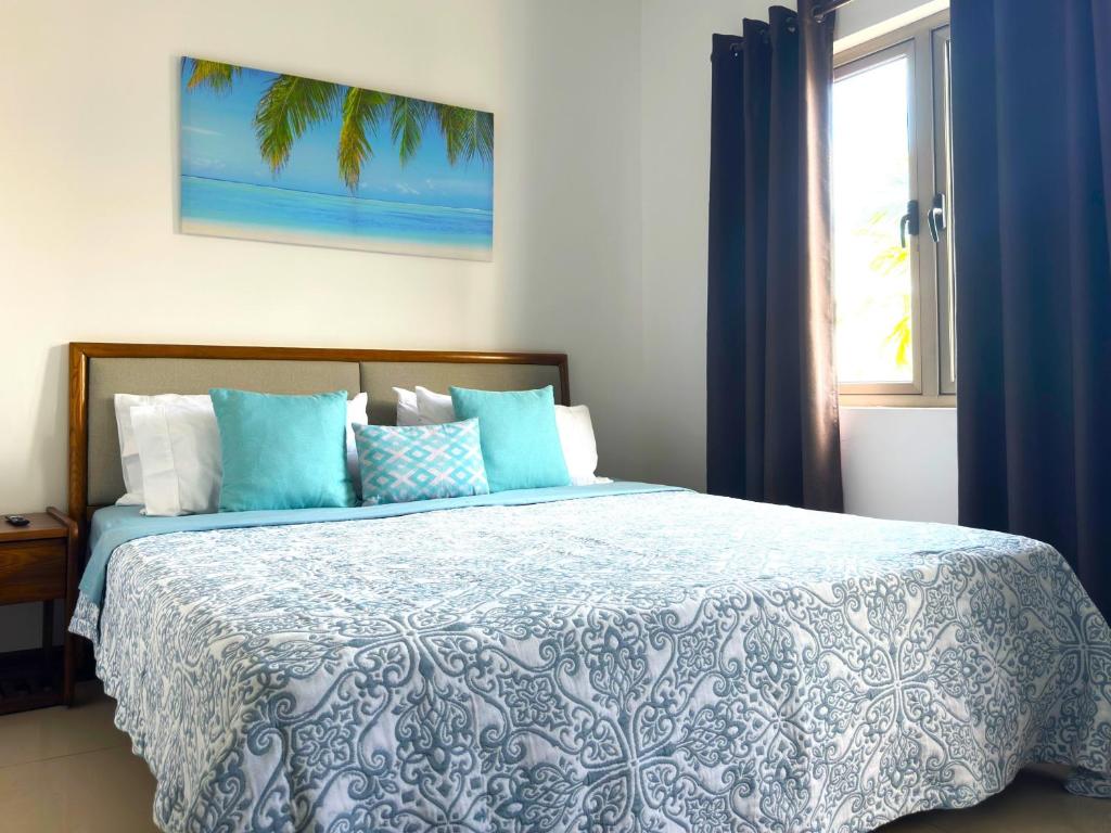 康隆尼角Residence Le Point Choisy的一间卧室配有一张带蓝色和白色床单的床和窗户。