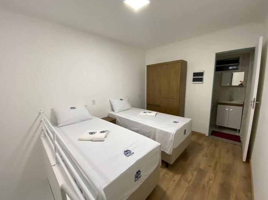 约恩维利Loft no Espinheiros - Joinville/SC的白色的客房设有两张床和橱柜。