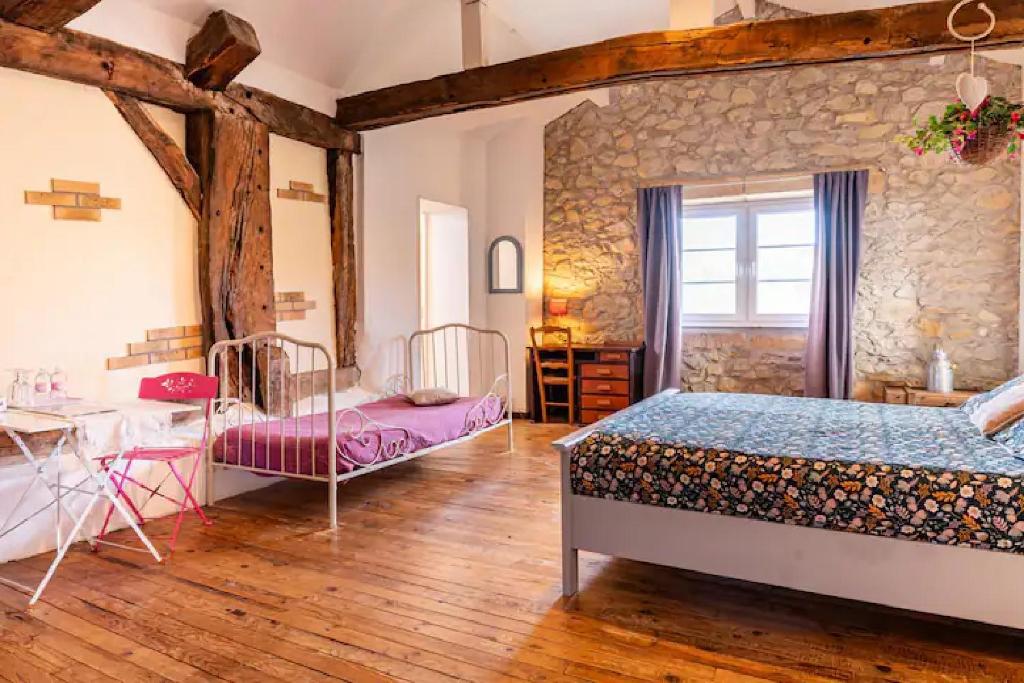 Saint-Martin-de-Seignanx莱斯埃库瑞杜塞克住宿加早餐旅馆的一间卧室设有两张床和石墙