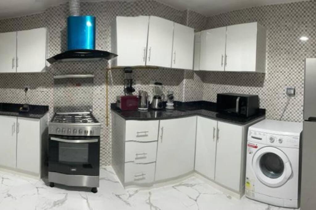 迪拜Private room available in Arjan.的厨房配有白色橱柜、炉灶和洗衣机。