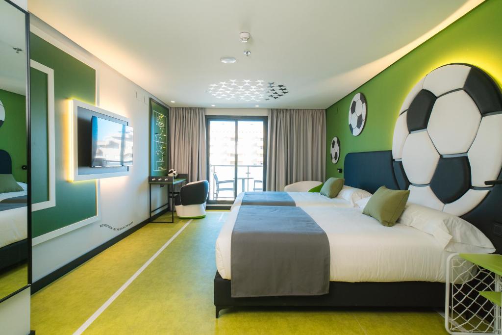 奥罗佩萨德尔马Hotel Magic Sports 4的卧室配有一张大床,墙上挂着足球球
