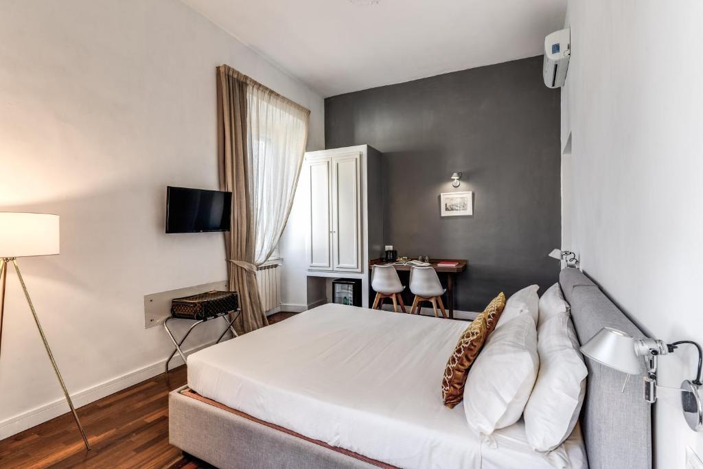 罗马瑞莱小女皇旅馆的卧室配有一张白色的大床和一张桌子