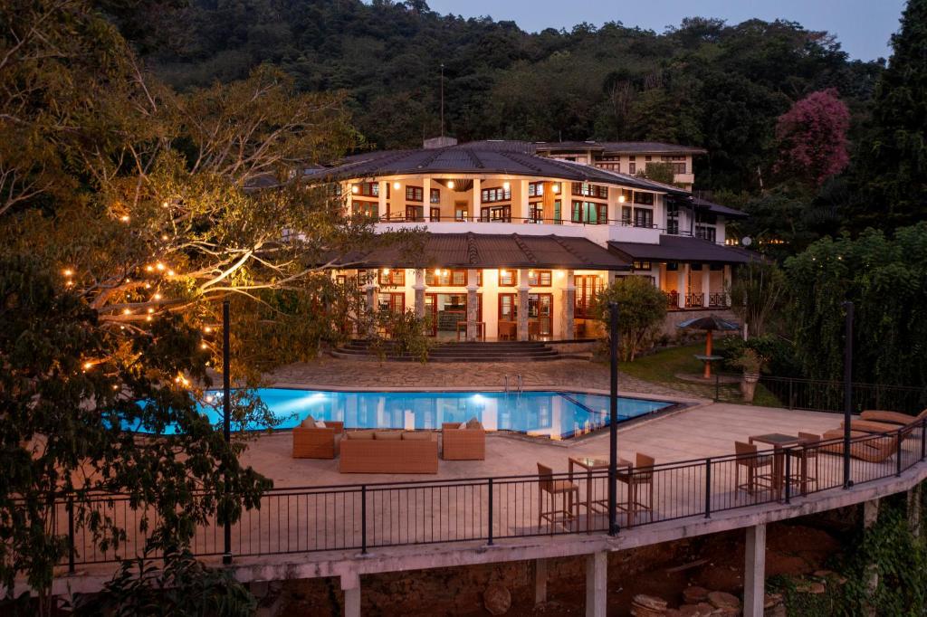 康提Indra Manel Family Holiday Resort Kandy的一座大房子,前面设有一个游泳池